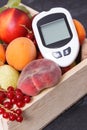 Glucometer for measuirng sugar level and fruits in wooden box as healthy snack or dessert containing natural vitamins Royalty Free Stock Photo