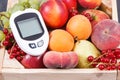 Glucometer for measuirng sugar level and fruits in wooden box as healthy snack or dessert containing natural vitamins Royalty Free Stock Photo