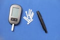 Glucometer with a needle on a blue background. Measurement of blood glucose
