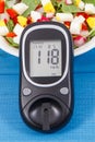 Glucometer with result of sugar level and fresh salad with eggs and vegetables, diabetes and healthy nutrition concept