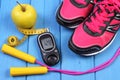 Glucometer, sport shoes, fresh apple and accessories for fitness on blue boards Royalty Free Stock Photo