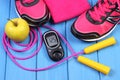 Glucometer, sport shoes, fresh apple and accessories for fitness on blue boards Royalty Free Stock Photo