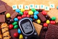 Glucometer, sweets and cane brown sugar with word diabetes, unhealthy food
