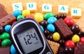 Glucometer, sweets and cane brown sugar with word sugar, unhealthy food