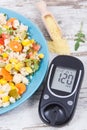 Glucose meter for checking sugar level and salad with vegetables and couscous groats. Light and healthy meal for diabetics