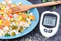 Glucose meter for checking sugar level and salad with vegetables and couscous groats. Light and healthy meal for diabetics