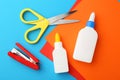 Glue, colorful paper, stapler and scissors on light blue background, flat lay Royalty Free Stock Photo