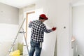 Glueing wallpapers at home. Young man, worker is putting up wallpapers on the wall. Home renovation concept Royalty Free Stock Photo
