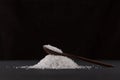 Glutamic acid monosodium salt in a wooden spoon on a dark background. Msg. Food additive E621. Flavor seasoning for enhancing food