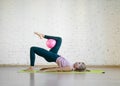 Gluteal bridge with pink small fit ball. Caucasian girl doing pilates with special equipment in fitness studio. Royalty Free Stock Photo