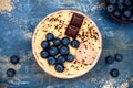 Gluten free amaranth and quinoa porridge breakfast bowl with blueberries and chocolate over rustic wooden background.