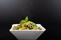 Gluten-free fresh cooked penne pasta from green peas isolated on black background, basil leaf top Royalty Free Stock Photo