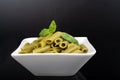 Gluten-free fresh cooked penne pasta from green peas isolated on black background, basil leaf top Royalty Free Stock Photo