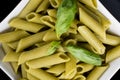 Gluten-free fresh cooked penne pasta from green peas isolated on black background, basil leaf top Royalty Free Stock Photo