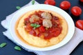 Gluten free meal from meatballs, vegetable ragout and polenta with tomato and basil on white plate on black background Royalty Free Stock Photo