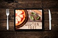 A gluten free pizza on  a rustic wood background displayed on a tablet pc Royalty Free Stock Photo