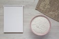 Gluten free rice flour in a pink bowl, blank notepad on a white wooden background, top view. Flat lay, overhead, from above. Copy Royalty Free Stock Photo