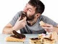 Glutton bearded man eating cupcakes with frenzy after long diet