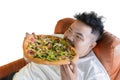 Gluttony fat man eating big pizza on the sofa