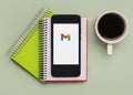 Gmail logo on black screen of smartphone with notebooks and cup of coffee Royalty Free Stock Photo