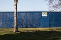 GMB Demolition danger keep out sign on a large blue solid fence wall with grass and a tree in front Royalty Free Stock Photo