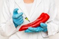 GMO scientist injecting liquid from syringe into red pepper Royalty Free Stock Photo