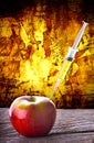 GMO syringe Injection into red apple dramatic background Royalty Free Stock Photo