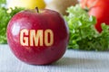 GMO text on red apple, vegetables and fruits in background, concept of genetically modified foods Royalty Free Stock Photo