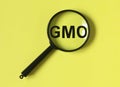 GMO word through magnifying glass. Text on yellow background