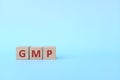 GMP word text on wooden blocks in blue background with copy space. Good manufacturing practice.
