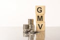 GMV - text on wooden cubes on white background with coins Royalty Free Stock Photo