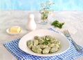 Gnocchi or dumplings with nettle or spinach on a white plate on a light gray background. Served with butter and parmesan cheese Royalty Free Stock Photo