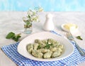 Gnocchi or dumplings with nettle or spinach on a white plate on a light gray background. Served with butter and parmesan cheese Royalty Free Stock Photo