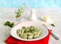 Gnocchi or dumplings with nettle or spinach on a white plate on a light gray background. Served with butter and parmesan cheese Royalty Free Stock Photo