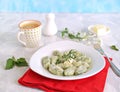 Gnocchi or dumplings with nettle or spinach on a white plate on a light gray background. Served with butter and parmesan cheese Royalty Free Stock Photo