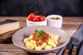 Gnocchi with grated parmesan cheese in tomato sauce on a wooden table with preparation components around it