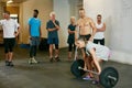 Go ahead, underestimate me. a woman lifting weights while a group of people in the background watch on. Royalty Free Stock Photo