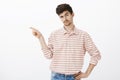 Go away from here, I demand. Studio shot of intrigued handsome male model with moustache, pointing left with index