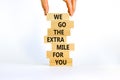 Go the extra mile symbol. Wooden blocks with words `We go the extra mile for you`. Businessman hand. Beautiful white background.