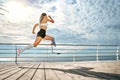 Go. Full-length of young disabled woman with leg prosthesis in sports clothing is running on the bridge Royalty Free Stock Photo