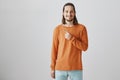 Go and grab your lucky place under sky. Portrait of handsome european male coworker in colorful orange sweater pointing