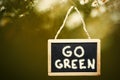 Go green written on black chalk board hanging from a tree. Royalty Free Stock Photo