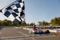 Go-kart driver crossing at finish line moving to checkered racing flag Royalty Free Stock Photo