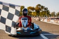 Go-kart driver crossing at finish line moving to checkered racing flag Royalty Free Stock Photo