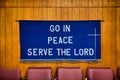 `Go in Peace Serve the Lord` written on Dark Blue Cloth hanging on the wall behind red chairs