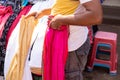 Goa, India, February 2023. Cropped photo of Indian man holding trousers, selling outdoors in local traditional market.