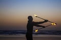 Fire juggler performing with fire sticks on the beach in Arambol