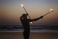 Fire juggler performing with fire sticks on the beach in Arambol