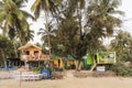 GOA, INDIA - MARCH 17, 2019: Bright colored tourist bungalows under palm trees on the sandy shore of the Indian ocean Royalty Free Stock Photo