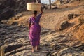 GOA, INDIA - MARCH 4: Woman in saris with basket on her head walks by Vagator beach on March 4, 2017 in Goa, India